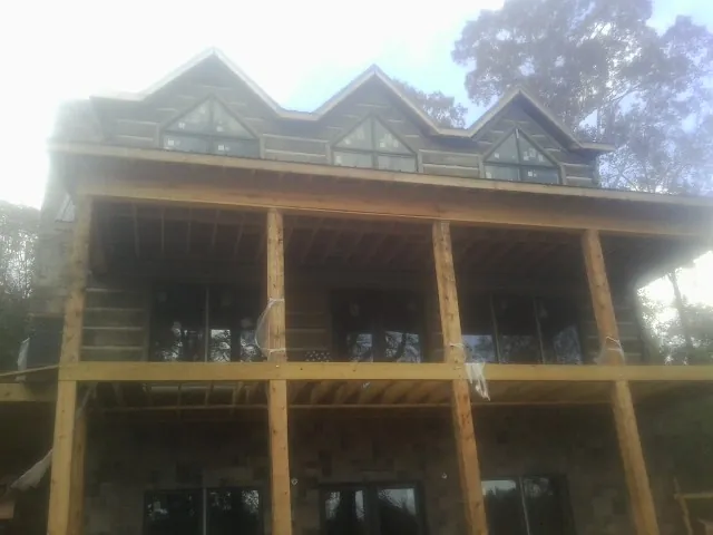 Dormers and porch framing on a large log home under construction — Roof Coating work by our crew in Fitchburg