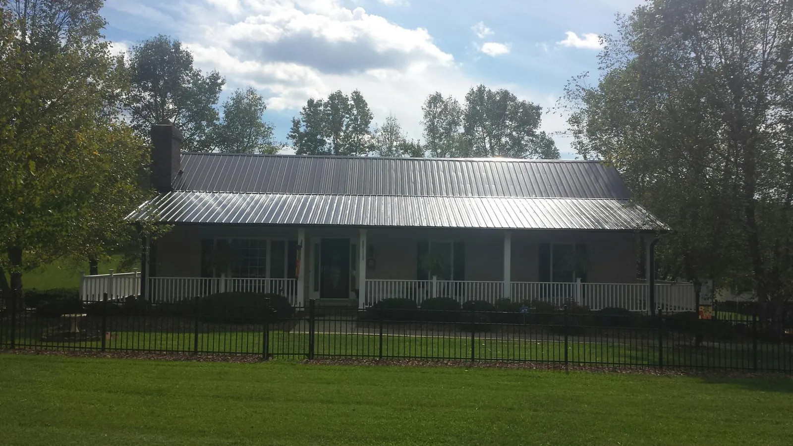 Gray metal roof on a brick ranch with a full width front porch — Gutter Guard Installation work by our crew in Fitchburg