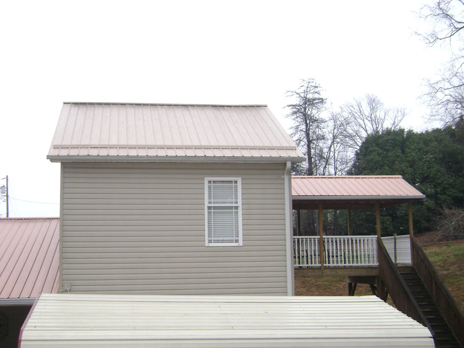 Tan metal roofs on a two story addition and attached porch, from a Roof Replacement job in Fitchburg